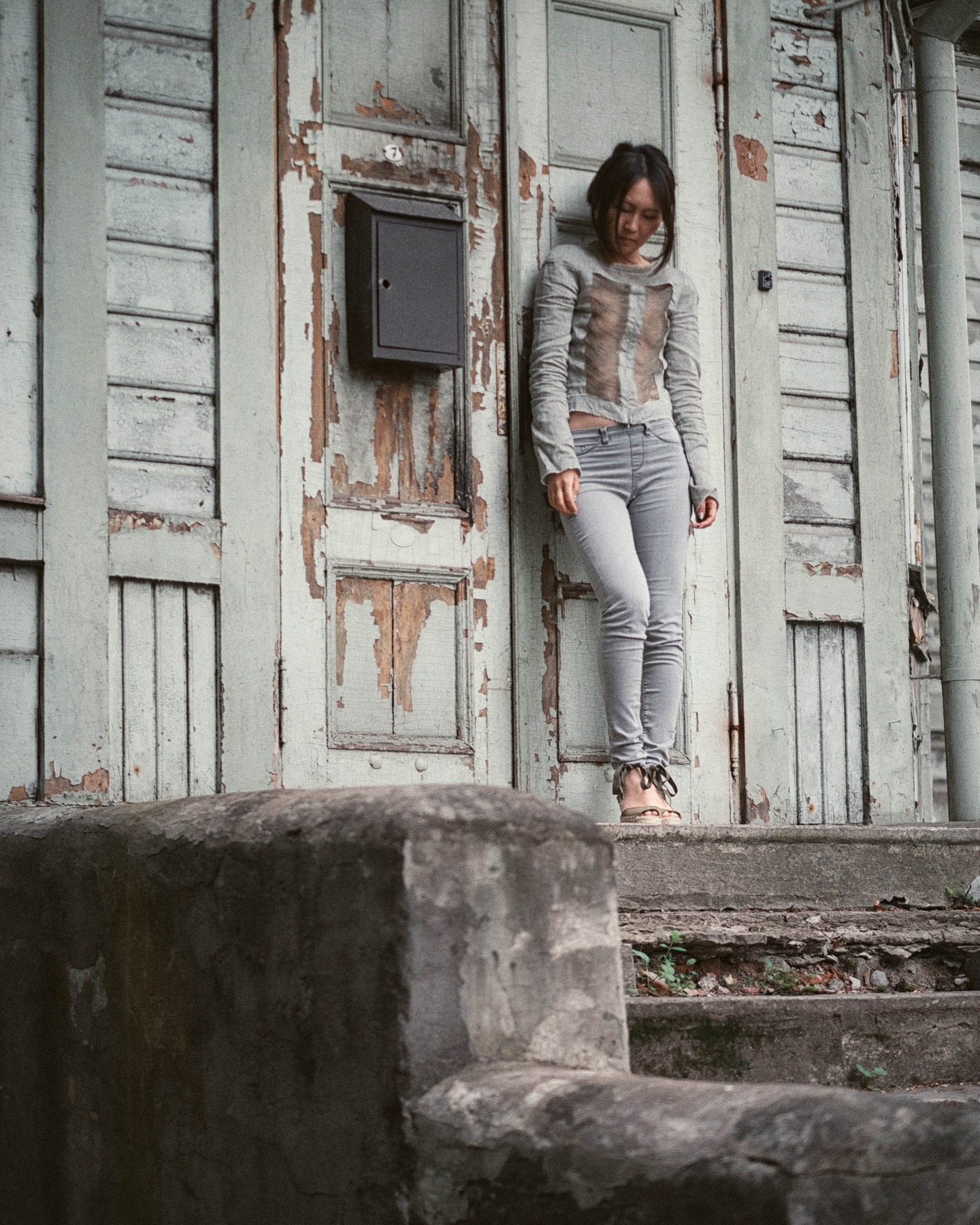 Lily-Yuri on steps outside a weathered wooden building in Tallinn