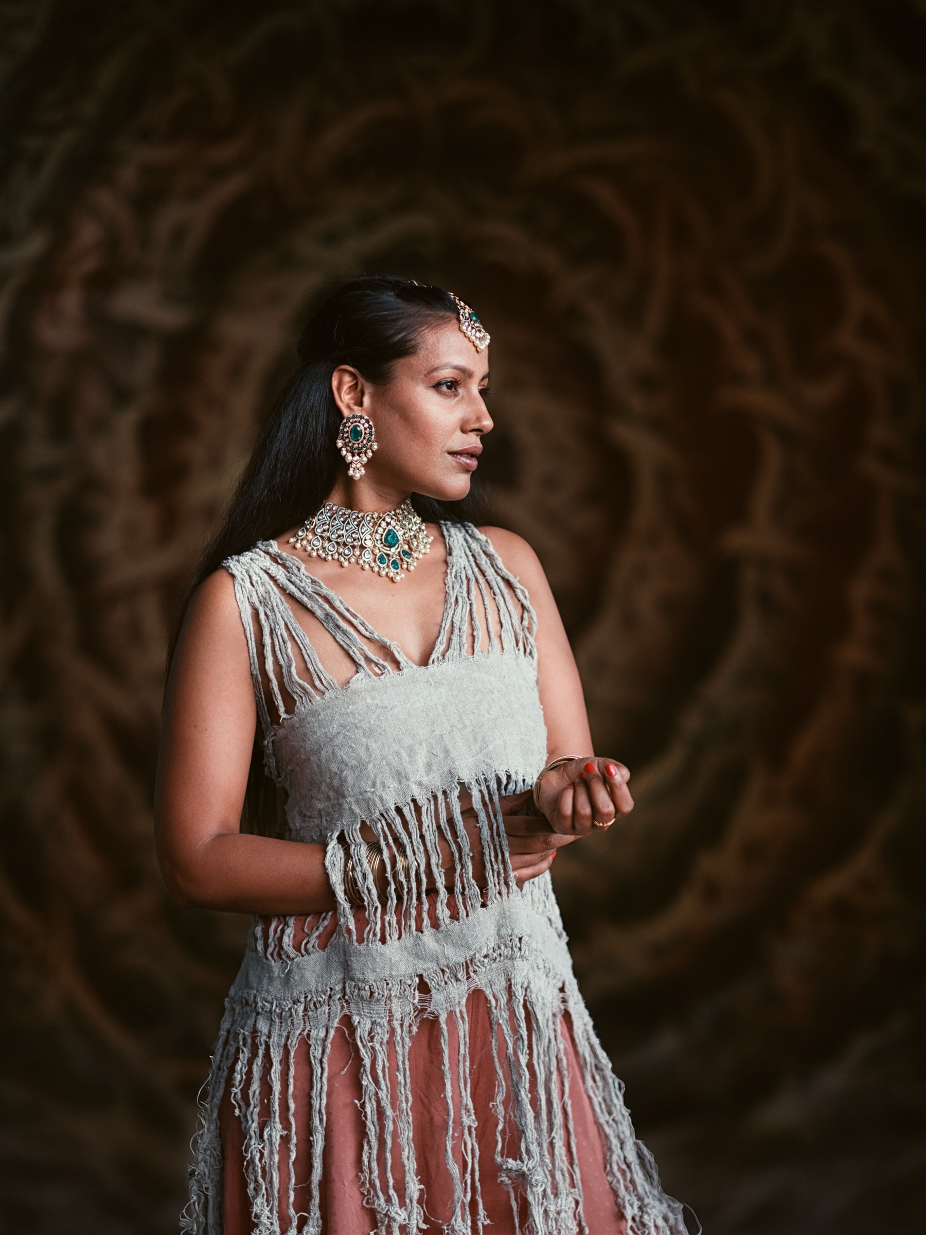 Portrait of Kiranmai Uppuluri in Kraków wearing jewellery and a handmade fringed linen dress